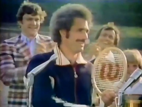 Tennis 70s style; big hair, mustache and wooden racket. (Wilson commercial, 1978)